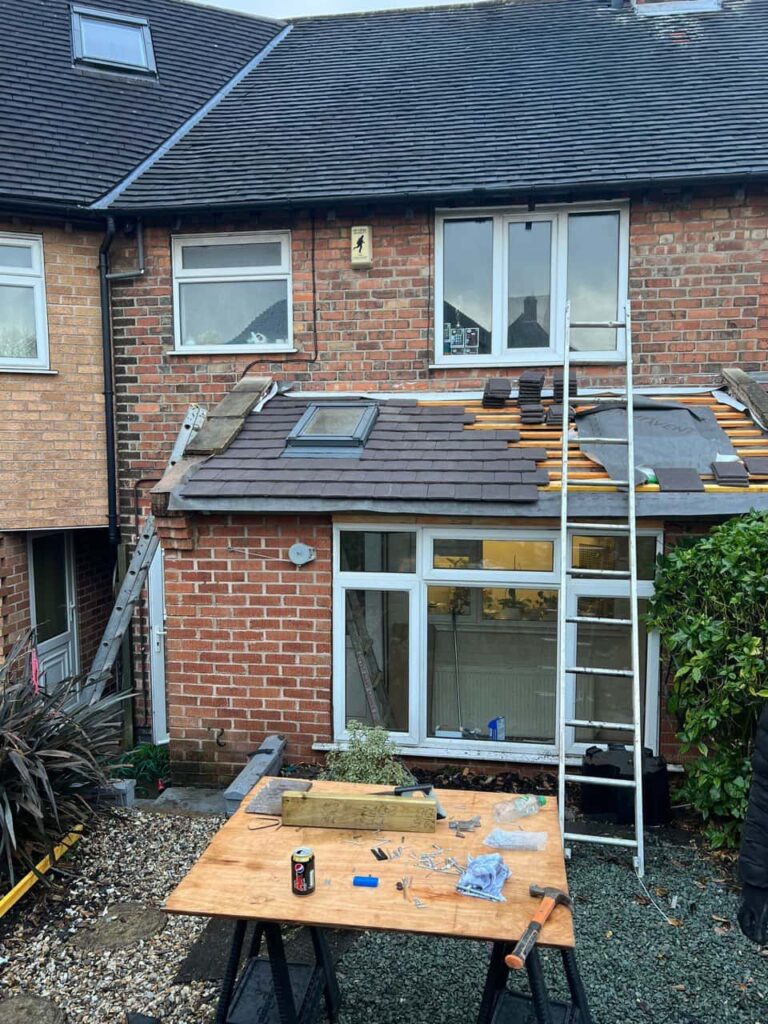 This is a photo of a roof extension that is having new roof tiles installed. This is a photo taken from the roof ridge looking down a tiled pitched roof on to a flat roof. Works carried out by Godstone Roofing Repairs