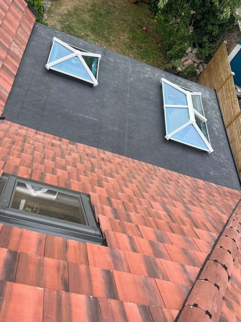 This is a photo taken from the roof ridge looking down a tiled pitched roof on to a flat roof. Works carried out by Godstone Roofing Repairs